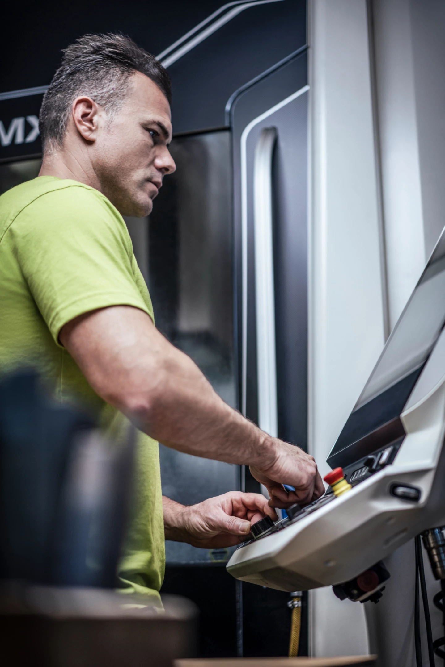 Mitarbeiter bedient eine CNC-Maschine über das Bedienelement in der Produktion von hepro production ag.