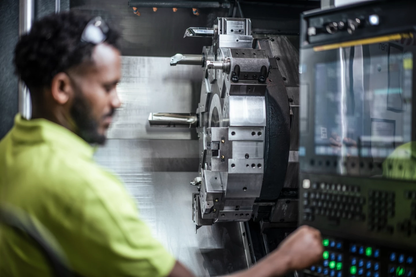 Mitarbeiter bedient eine CNC-Drehmaschine in der Produktion von hepro production ag; im Fokus stehen das Werkzeugrevolver-System und das digitale Bedienpanel.