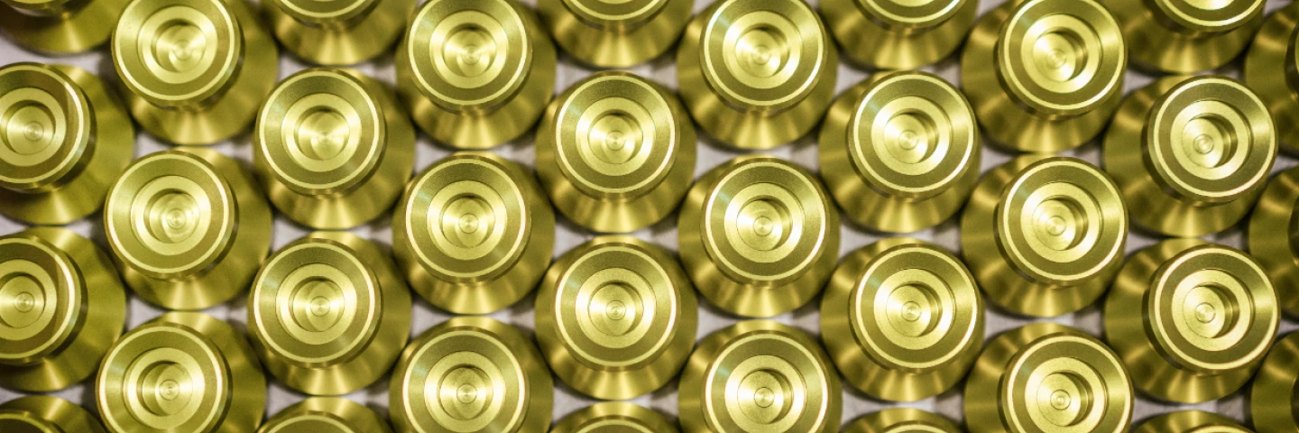 Serienfertigung identischer, goldfarbener Präzisionsdrehteile aus Metall, sauber angeordnet nach der Bearbeitung, als finales Endprodukt von hepro production ag mit hoher Wiederholgenauigkeit und gleichbleibender Qualität.