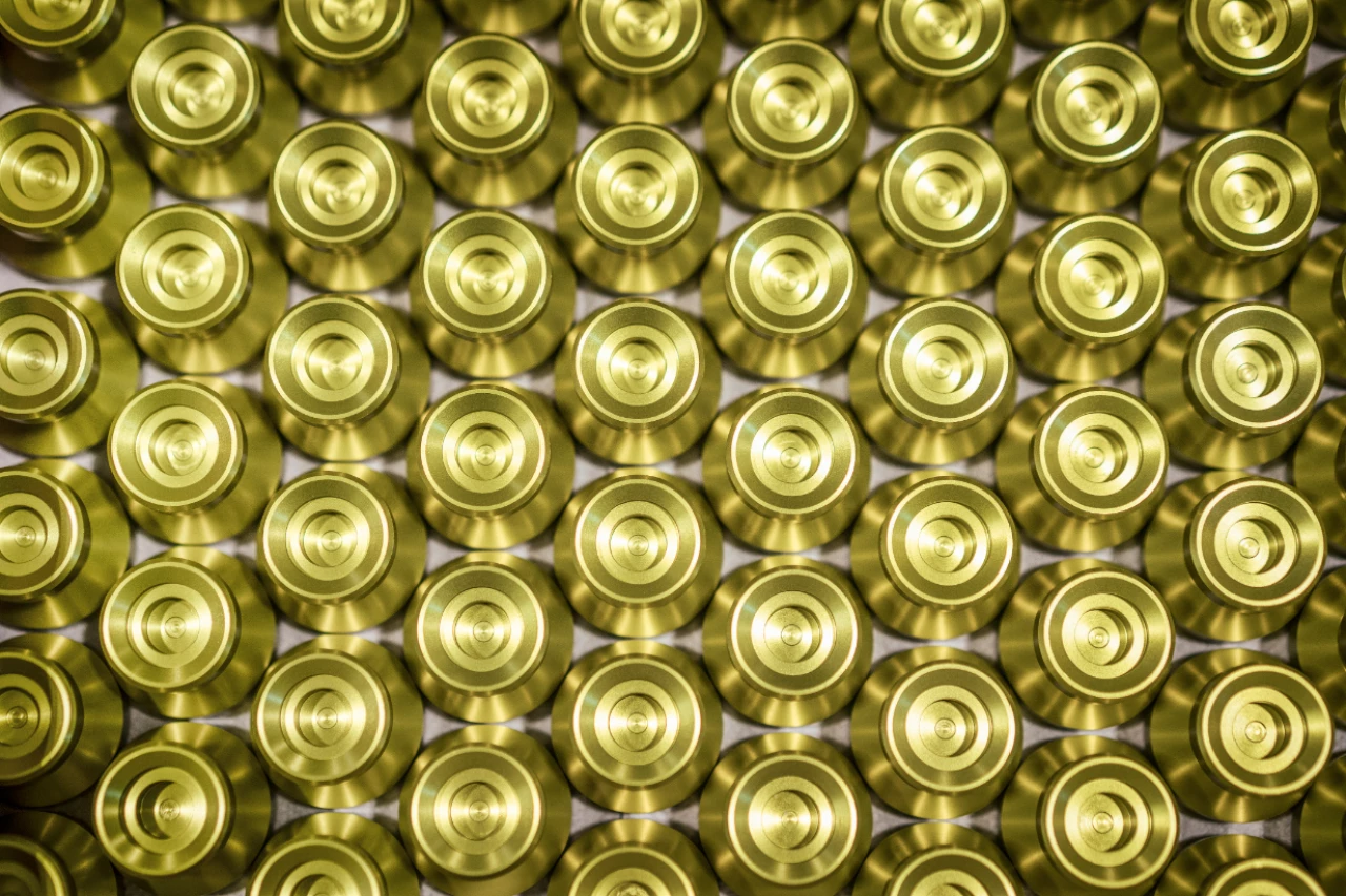 Serienfertigung identischer, goldfarbener Präzisionsdrehteile aus Metall, sauber angeordnet nach der Bearbeitung, als finales Endprodukt von hepro production ag mit hoher Wiederholgenauigkeit und gleichbleibender Qualität.