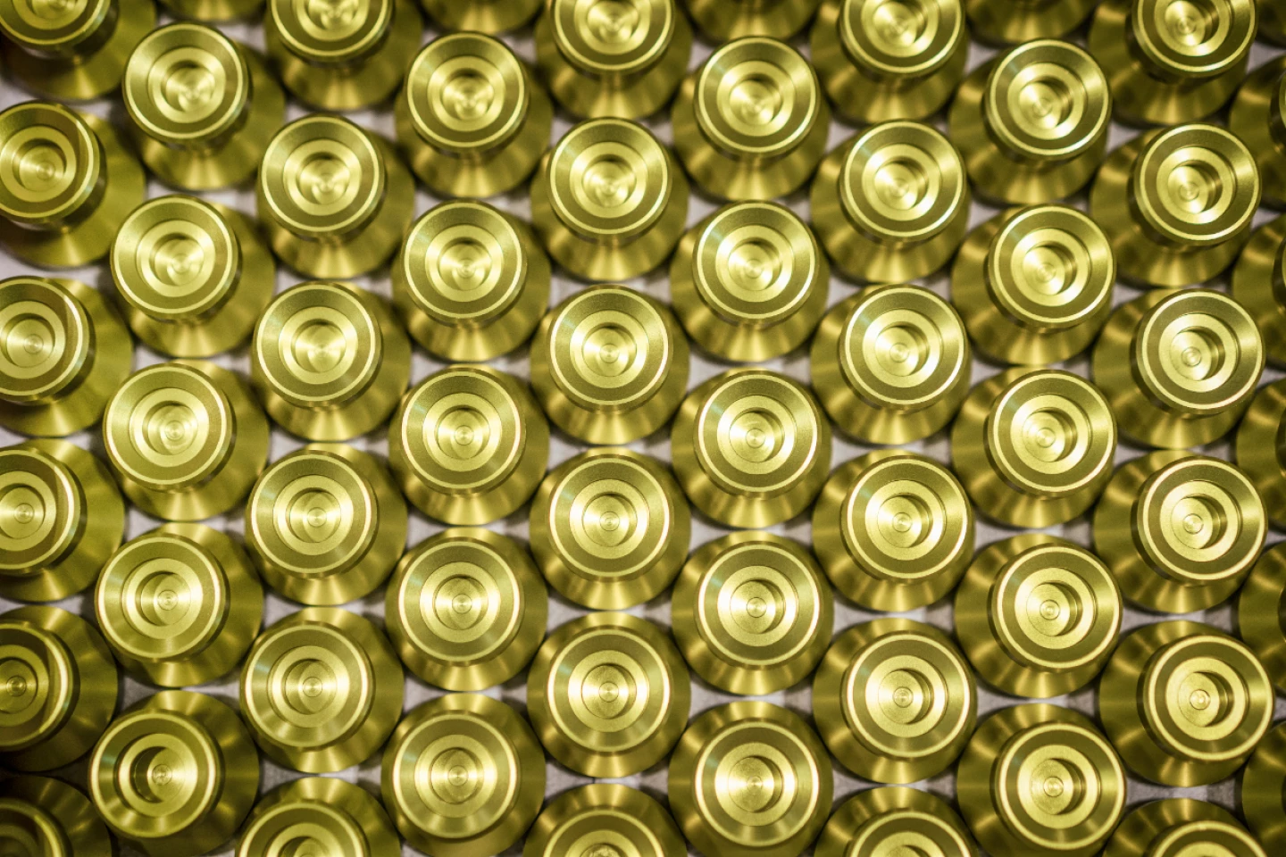 Serienfertigung identischer, goldfarbener Präzisionsdrehteile aus Metall, sauber angeordnet nach der Bearbeitung, als finales Endprodukt von hepro production ag mit hoher Wiederholgenauigkeit und gleichbleibender Qualität.