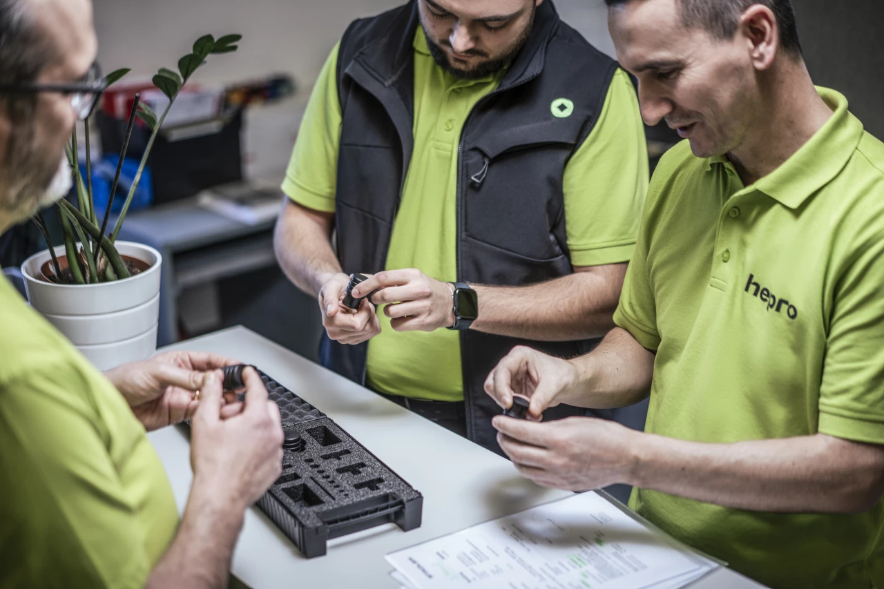 Mitarbeitende von hepro production ag prüfen und montieren gemeinsam Präzisionsteile zu einer Komplettlösung an einem Arbeitsplatz.