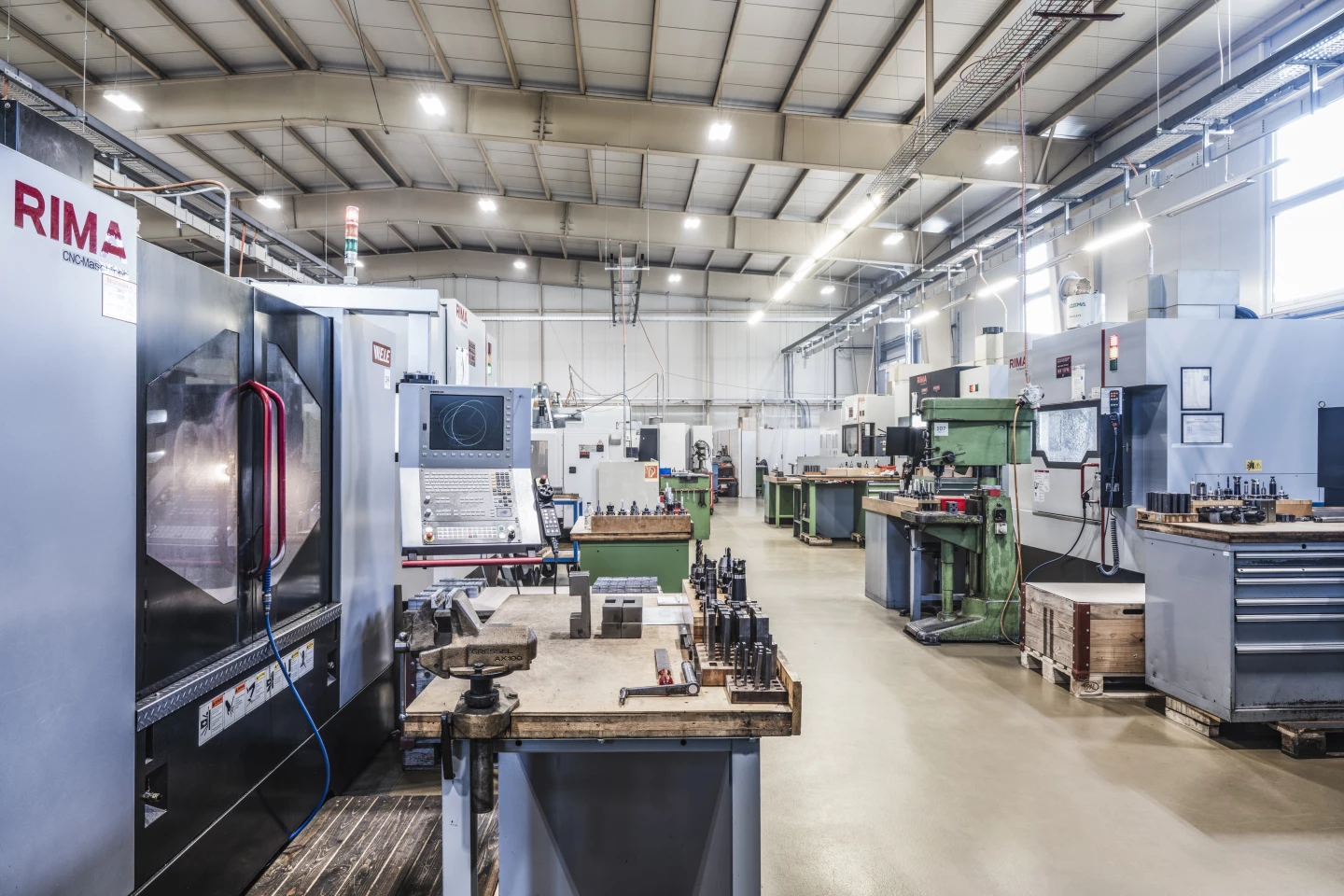 Blick in die Produktionshalle von hepro production ag mit CNC-Maschinen, Werkzeugarbeitsplätzen und strukturierter Fertigungsumgebung.